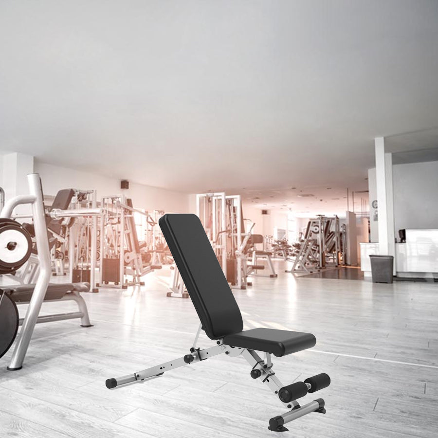 Black weight bench in a gym setting with exercise equipment in the background