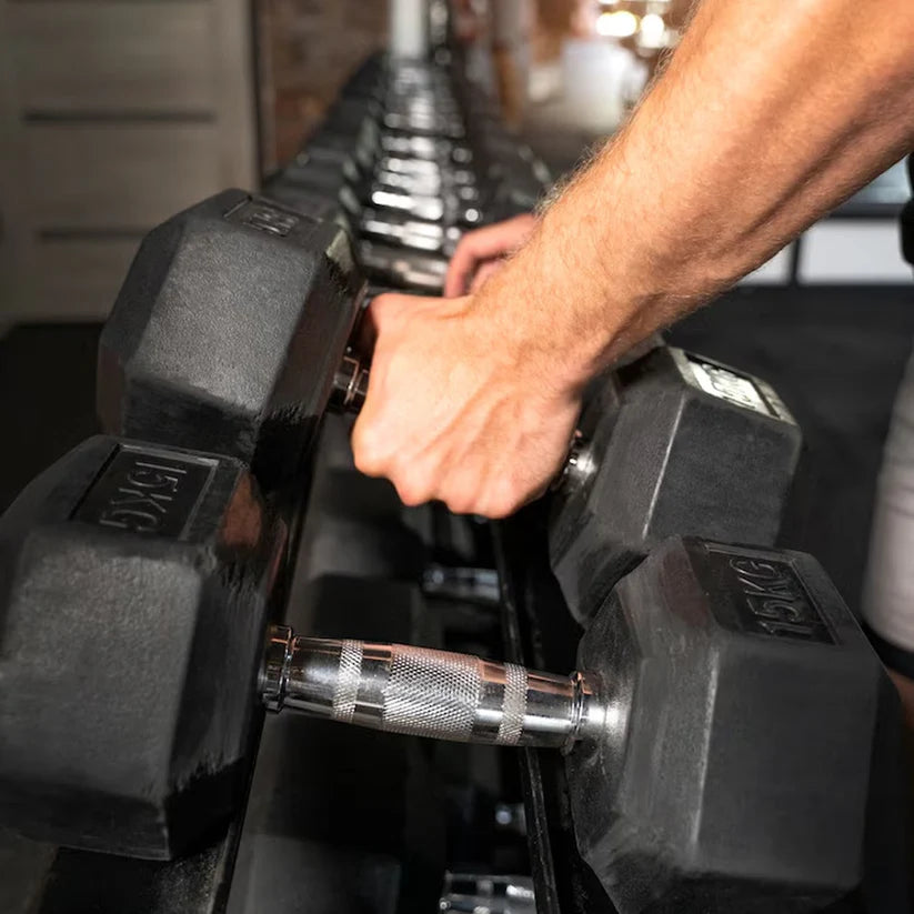 Person holding a pair of dumbbells in a gym setting