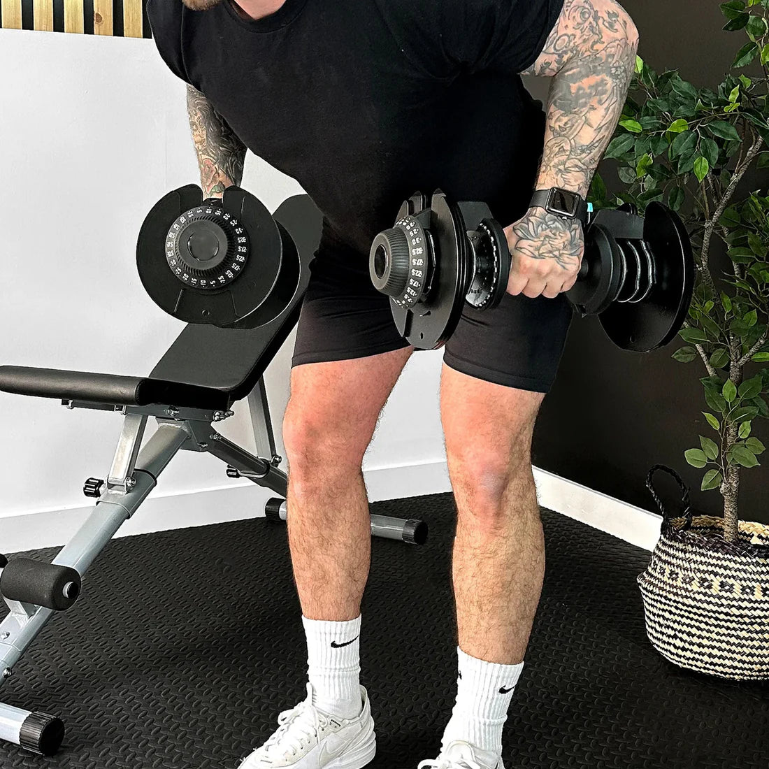Man performing push-ups with adjustable dumbbells on a gym floor.