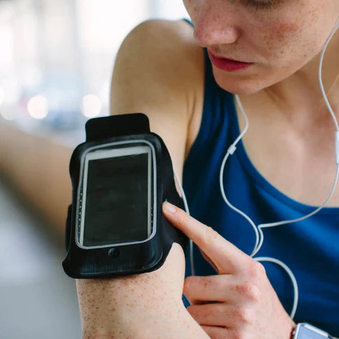 Person using a smartphone in an armband with earphones, blurred background