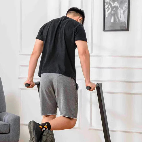 Person using a stair stepper in a home setting with a white wall and framed picture in the background.