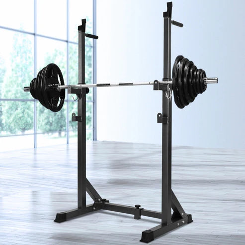 Barbell with weights on a squat rack in a room with large windows.
